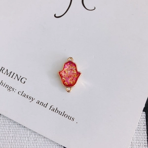 Détail du pendentif Main de Fatma en résine rose et feuilles d'or à double anneau