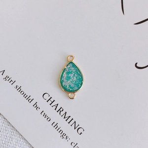 Detail of green teardrop pendant with gold metal frame and double hanging loops for DIY jewelry
