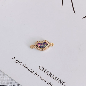 Detailed view of gold-plated lip charm with zircon inlay and colorful glitter center