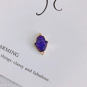 Détail d'un connecteur main de Hamsa doré avec résine pailletée violette pour bijoux DIY