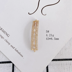 Detail view of gold-plated rectangular jewelry pendant with zircon stones and loops