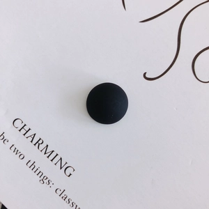 Close-up of matte black resin half-round beads showing fine frosted texture on white paper