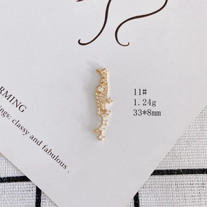Detailed view of a gold-plated lizard pendant with white pavé stones on a white card
