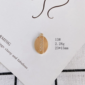 Detailed view of gold-plated comb pendant with white rhinestones and feather texture