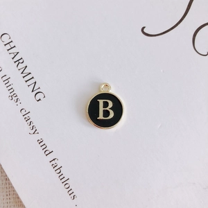 Macro view of gold-plated alloy pendant with black oil drip and golden letter B