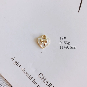 Vue macro d'un pendentif cœur en émail blanc avec nœud doré et anneau de connexion
