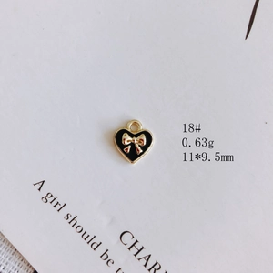 Détail macro du pendentif cœur en émail noir avec nœud doré et anneau de suspension