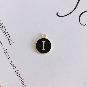 Macro shot of round black enamel 'I' letter pendant with gold trim for DIY jewelry making