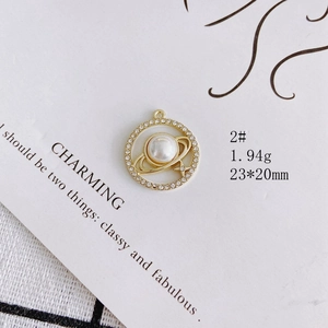 Macro view of a gold Saturn pendant charm with pearl and crystals for jewelry DIY