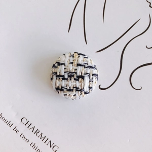 Close-up of houndstooth tweed button with black, white, and gold metallic threads