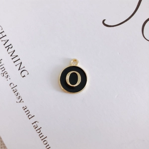 Detail of round black enamel pendant with gold letter O for DIY jewelry making