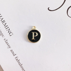 Macro detail of round alloy pendant with black enamel finish and golden letter P