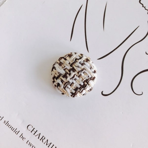 Macro shot of houndstooth tweed fabric button with gold metallic threads and texture