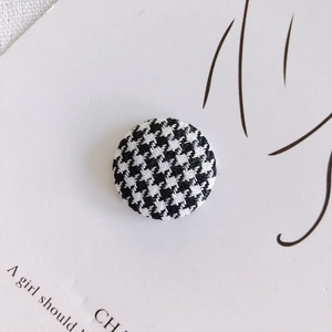 Macro view of a classic black and white houndstooth fabric button on a card