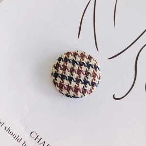 Macro view of round houndstooth fabric buttons for sweaters with textured weave detail