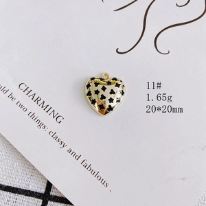 Detail of heart-shaped gold alloy pendant with black enamel star and clover motifs