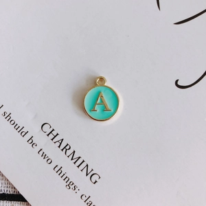 Detailed macro view of mint green enamel letter A pendant with golden metal border