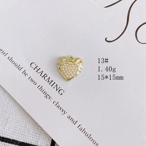 Close-up of a 15x15mm golden heart-shaped jewelry pendant with white pearl inlay