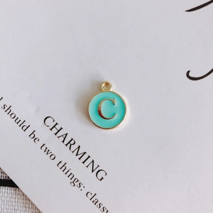 Close-up of golden round letter C charm with tiffany blue enamel for DIY jewelry