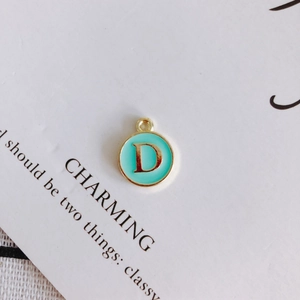 Detailed close-up of a gold-edged round enamel pendant with letter D for DIY jewelry