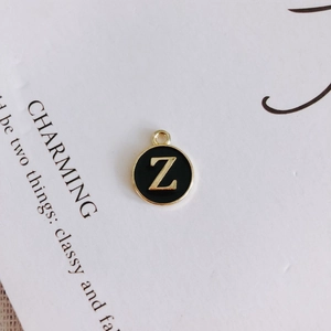 Detail of round black enamel pendant with gold-plated letter Z for DIY jewelry