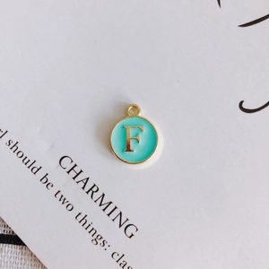 Macro view of gold letter F pendant with green enamel finish for DIY jewelry making