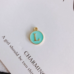 Detail of round gold-plated letter L pendant with light blue enamel for DIY jewelry