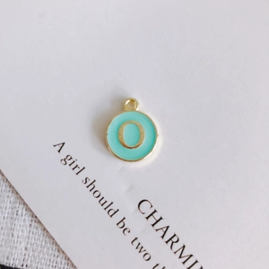Detail of round mint green enamel letter O pendant with gold plated edges for DIY jewelry