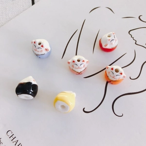 Macro detail of hand-painted ceramic Maneki-neko beads for DIY jewelry making