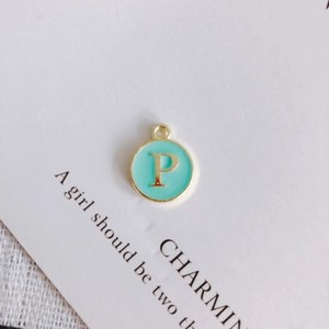 Detail of round gold-edged pendant with mint green enamel and letter P for DIY jewelry