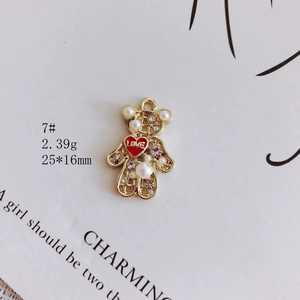 Macro shot of bear-shaped gold alloy pendant with pearls, rhinestones and red love heart