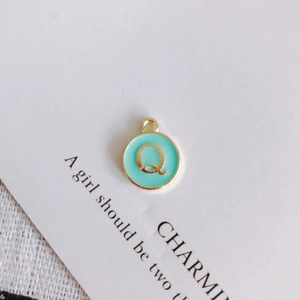 Detailed view of mint green enamel letter Q charm with gold-plated alloy finish