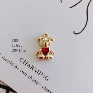Macro view of golden bear pendant with red heart gemstone and size specifications
