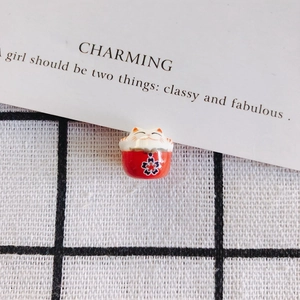 Macro detail of red ceramic Maneki Neko charm with hand-painted cherry blossom pattern