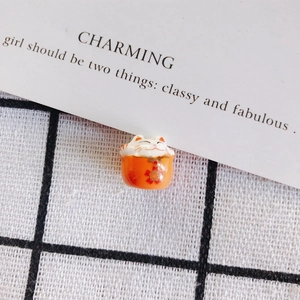 Macro detail of hand-painted orange ceramic fortune cat bead on checkered background