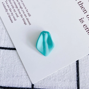 Close-up of mint green resin petal charms with pre-drilled holes for DIY jewelry making