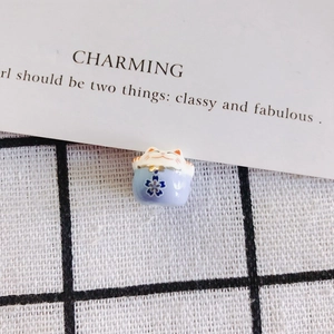 Macro shot of handcrafted light blue ceramic lucky cat beads with plum blossom patterns