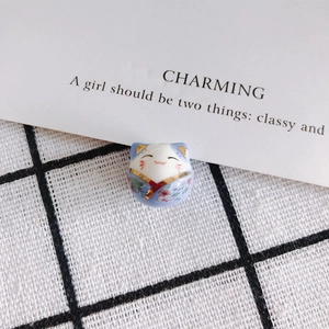 Detail of hand-painted Maneki Neko ceramic bead with gold gilding and purple kimono pattern