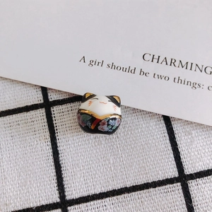 Macro detail of hand-painted ceramic lucky cat beads with gold accents and floral patterns