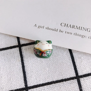 Macro view of green ceramic lucky cat bead with pink cherry blossom and golden details
