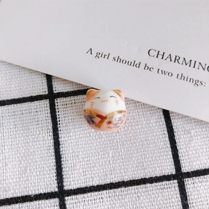 Detailed close-up of a handcrafted ceramic lucky cat bead with floral kimono patterns
