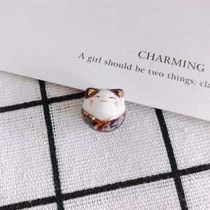 Detailed view of handmade ceramic lucky cat bead with purple floral kimono design
