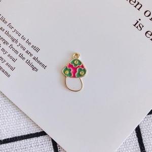 Macro view of green enamel mushroom pendant with pink flower on artistic card