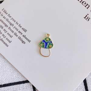 Close-up of blue enamel mushroom charm with green floral pattern for DIY jewelry