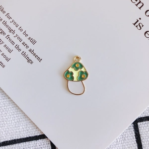 Detail of yellow and green mushroom alloy pendant for DIY jewelry on a book background