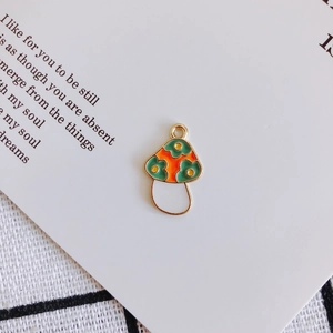 Detail of DIY mushroom pendant with orange enamel and green floral patterns