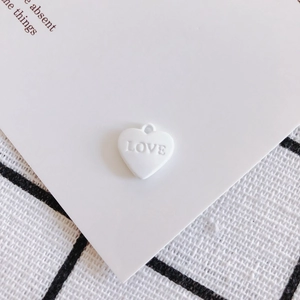 Dettaglio di un ciondolo a cuore bianco in lega con scritta LOVE per gioielli fai-da-te