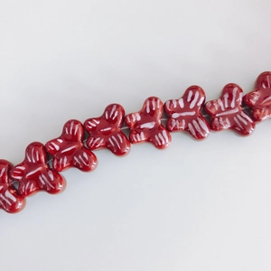 Detailed view of red ceramic butterfly beads with white hand-painted stripes for DIY jewelry