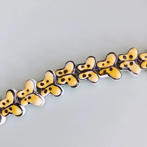 Detailed top view of handmade yellow butterfly ceramic beads for DIY jewelry making