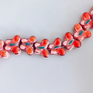 Close-up of vibrant orange and green ceramic butterfly beads for DIY jewelry making